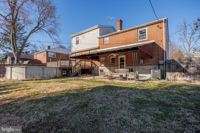 back of house featuring fence, a patio area, brick siding, and a lawn