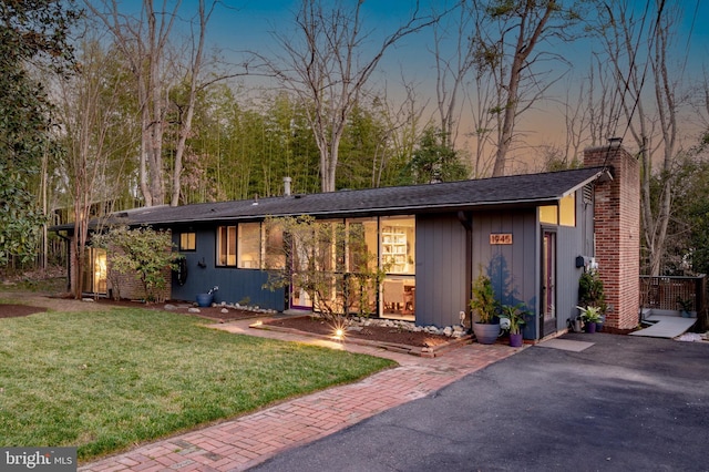 mid-century modern home with a chimney and a front yard