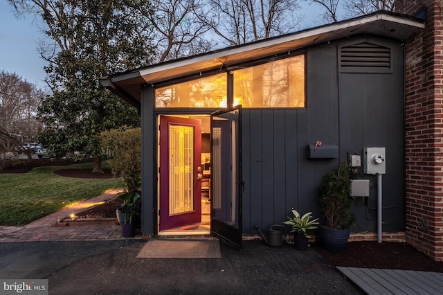 doorway to property featuring brick siding and a lawn