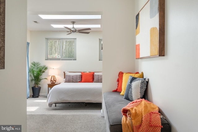 carpeted bedroom featuring ceiling fan, visible vents, and a skylight