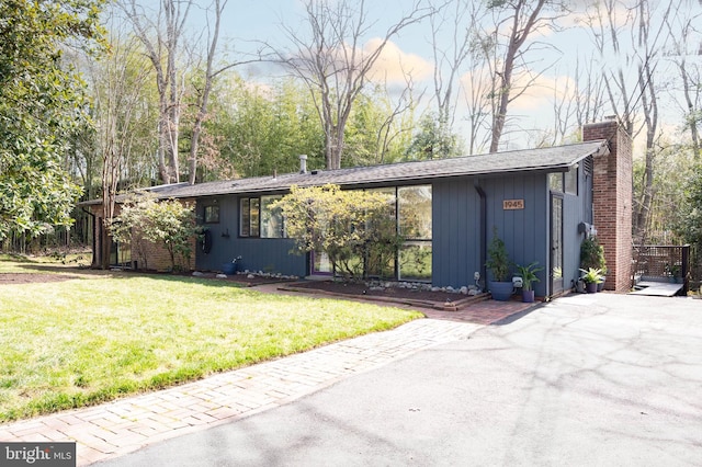 mid-century home with a front lawn and a chimney