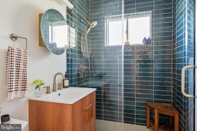 bathroom with tiled shower and vanity