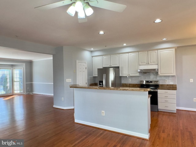 kitchen with under cabinet range hood, dark wood finished floors, stainless steel appliances, white cabinets, and decorative backsplash