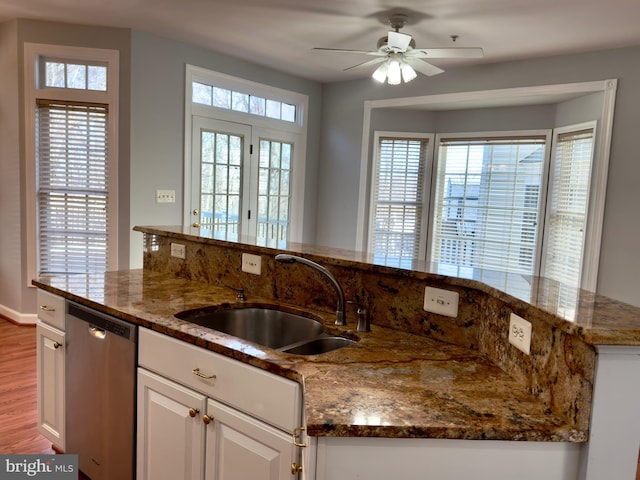 kitchen with a sink, stainless steel dishwasher, a healthy amount of sunlight, and white cabinets