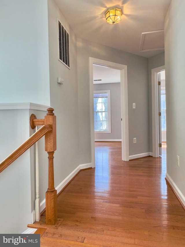 hall featuring light wood-style floors, visible vents, and baseboards