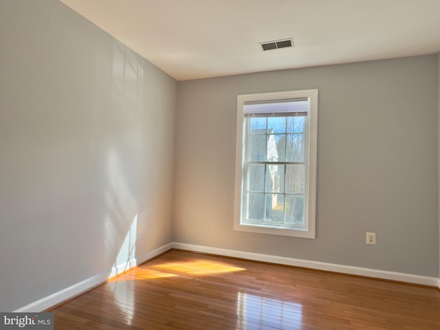 unfurnished room featuring visible vents, baseboards, and hardwood / wood-style flooring