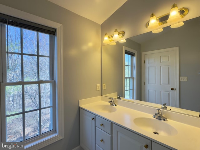 full bathroom featuring double vanity, vaulted ceiling, and a sink