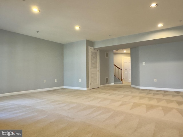 spare room with stairway, recessed lighting, light colored carpet, and baseboards