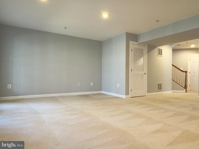 unfurnished room with stairs, light colored carpet, visible vents, and baseboards