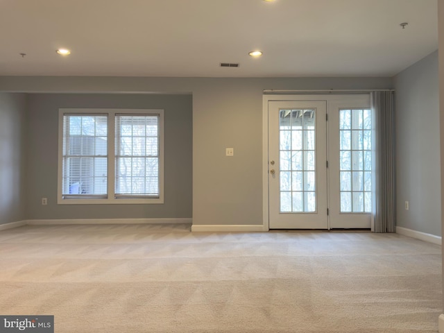 doorway to outside featuring a healthy amount of sunlight, baseboards, visible vents, and light carpet