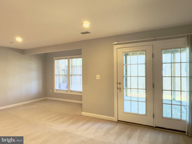 doorway to outside featuring visible vents, baseboards, light colored carpet, and plenty of natural light