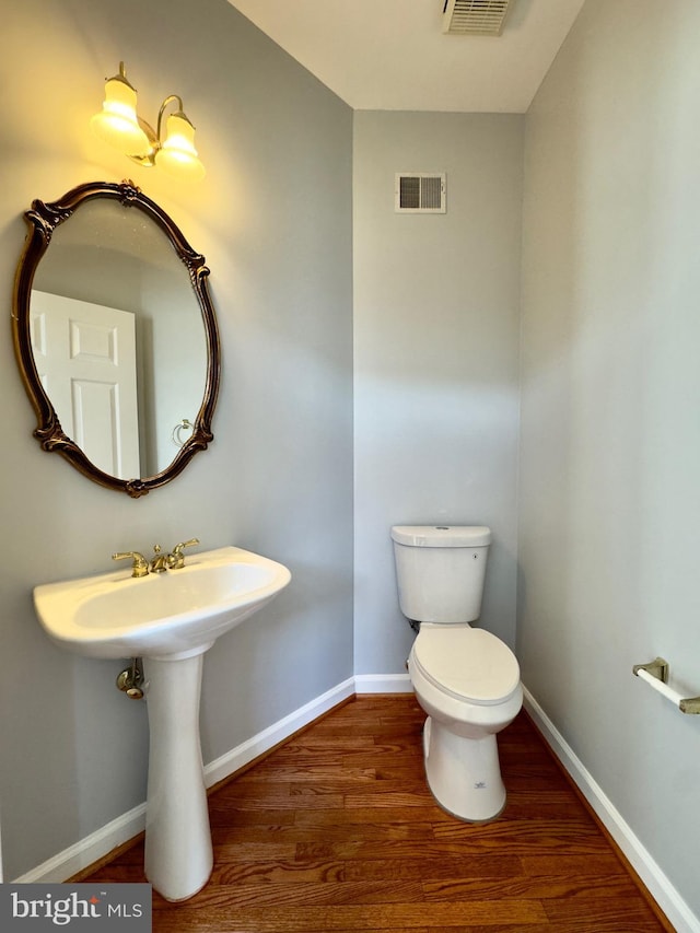 bathroom featuring visible vents, baseboards, toilet, and wood finished floors