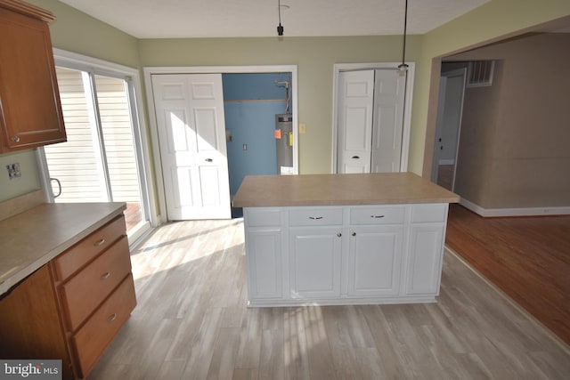 kitchen featuring light countertops, light wood-style floors, a kitchen island, and electric water heater