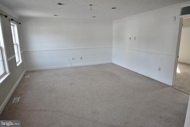 carpeted empty room with visible vents, a textured ceiling, baseboards, and ornamental molding