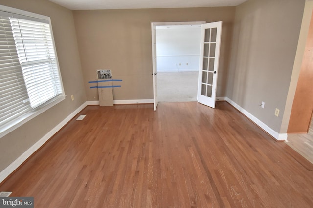 empty room featuring visible vents, baseboards, and wood finished floors