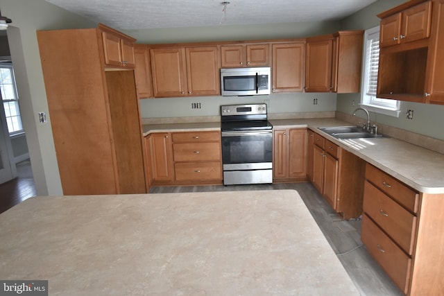 kitchen featuring a sink, stainless steel appliances, light wood-style floors, and light countertops