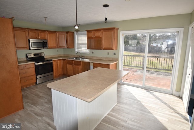 kitchen with stainless steel appliances, light countertops, light wood-style floors, and a sink