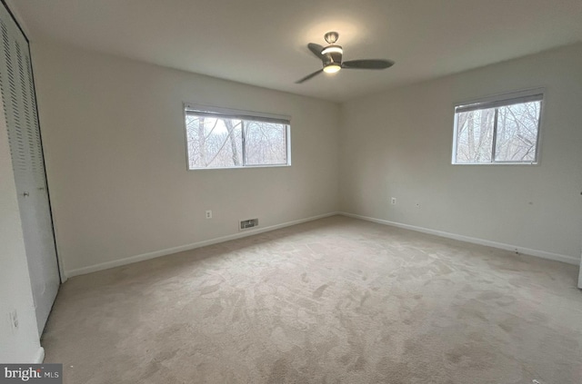 unfurnished bedroom featuring a ceiling fan, baseboards, visible vents, a closet, and light carpet