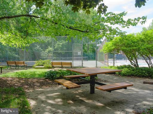 view of community featuring a tennis court and fence