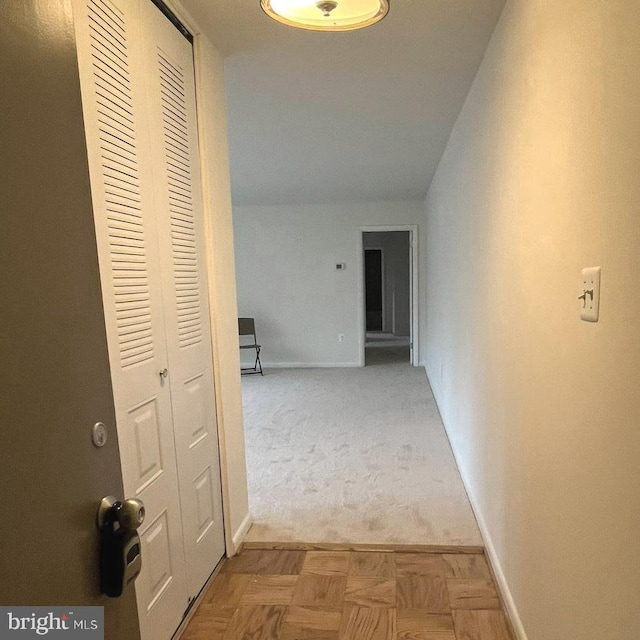 corridor featuring light colored carpet, baseboards, and lofted ceiling