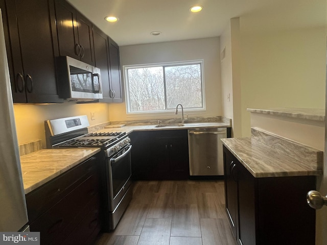 kitchen with recessed lighting, dark wood-style flooring, a sink, appliances with stainless steel finishes, and dark cabinets