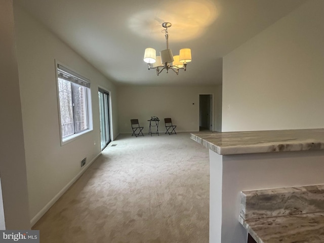 unfurnished living room with baseboards, light carpet, an inviting chandelier, and visible vents