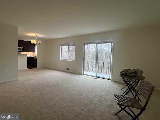 unfurnished living room with visible vents, baseboards, light colored carpet, and a chandelier