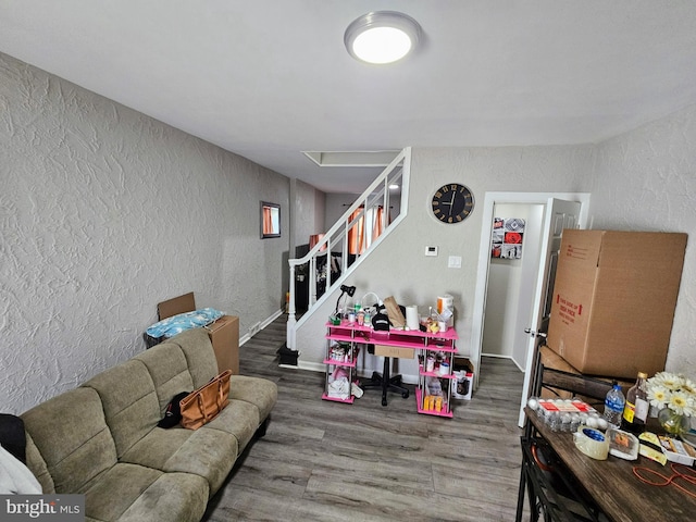 living room with baseboards, wood finished floors, stairs, and a textured wall