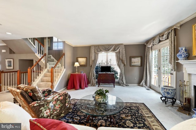 living area featuring stairway, baseboards, carpet floors, a fireplace with flush hearth, and crown molding