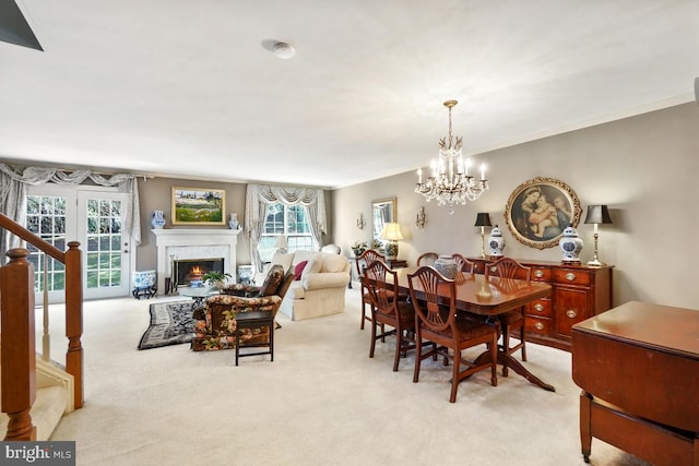 dining room featuring light carpet, a notable chandelier, a warm lit fireplace, and ornamental molding