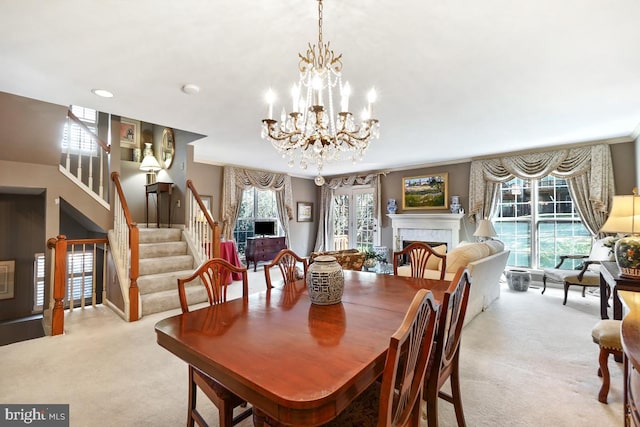 dining space with stairway, light colored carpet, a fireplace, and an inviting chandelier