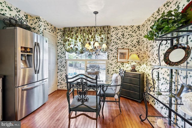 dining room with wallpapered walls, an inviting chandelier, and hardwood / wood-style floors