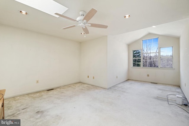 empty room featuring a ceiling fan, baseboards, carpet floors, recessed lighting, and lofted ceiling with skylight