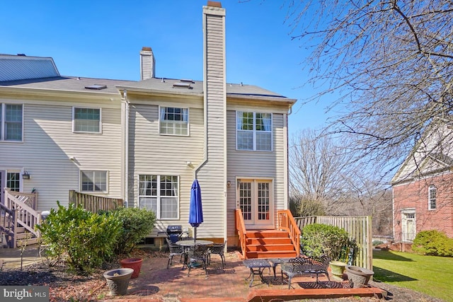 rear view of property with a lawn, entry steps, a chimney, and a patio