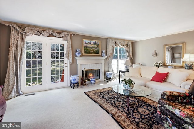 carpeted living area featuring a tiled fireplace, visible vents, and ornamental molding