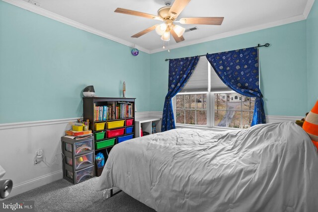 carpeted bedroom featuring visible vents, baseboards, ornamental molding, and a ceiling fan