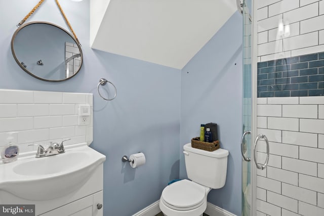 bathroom featuring tiled shower, toilet, vanity, and baseboards