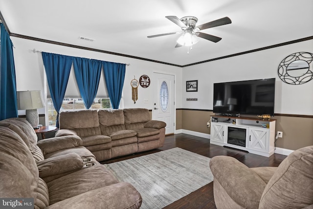 living room featuring a ceiling fan, baseboards, visible vents, ornamental molding, and dark wood-type flooring