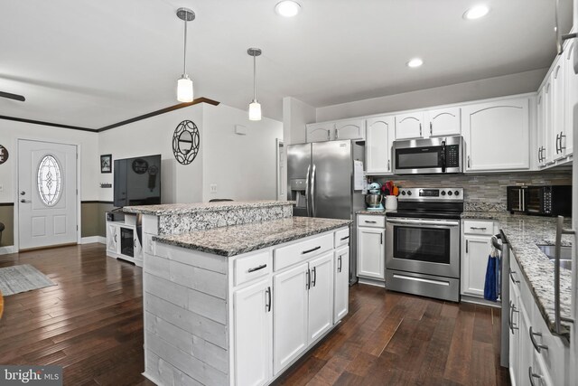 kitchen featuring dark wood-style floors, stainless steel appliances, white cabinets, tasteful backsplash, and a center island