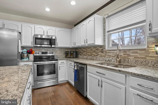 kitchen with a sink, dark wood-type flooring, appliances with stainless steel finishes, white cabinetry, and tasteful backsplash