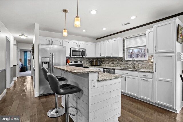 kitchen with visible vents, a sink, stainless steel appliances, white cabinets, and backsplash