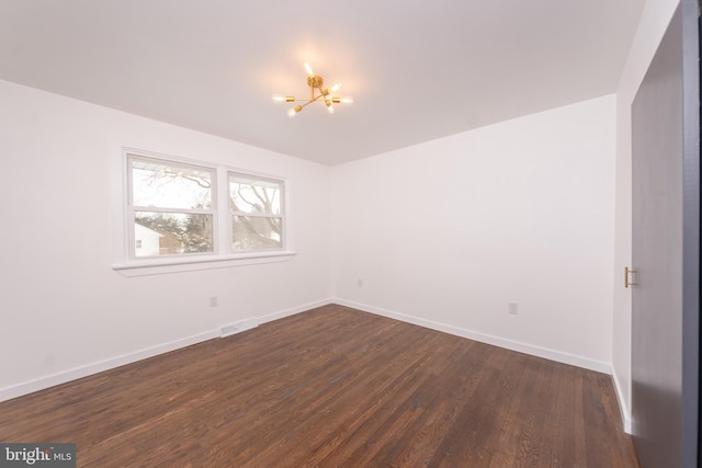 empty room with visible vents, baseboards, a notable chandelier, and dark wood-style floors