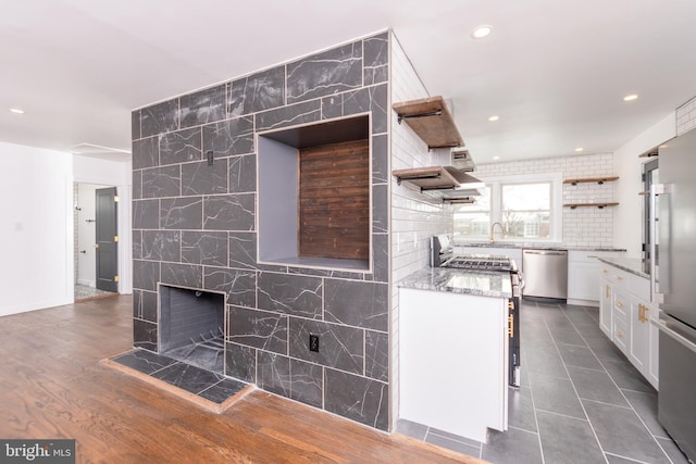 kitchen featuring open shelves, light stone counters, white cabinetry, appliances with stainless steel finishes, and decorative backsplash