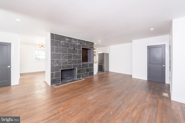 unfurnished living room with wood finished floors, recessed lighting, a fireplace, and baseboards