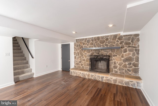 unfurnished living room with stairway, baseboards, wood finished floors, and a fireplace