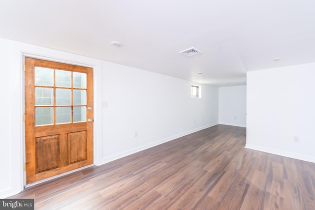 empty room with dark wood-style floors, visible vents, and baseboards