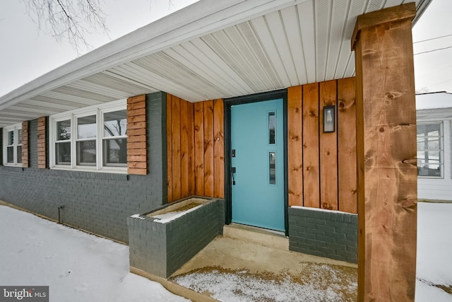 view of exterior entry with brick siding and board and batten siding