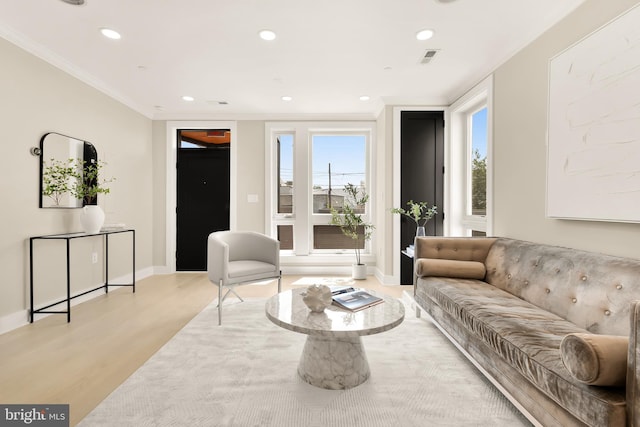 living area with baseboards, visible vents, recessed lighting, ornamental molding, and light wood-type flooring