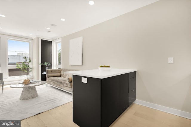 interior space featuring recessed lighting, baseboards, dark cabinets, and light wood finished floors