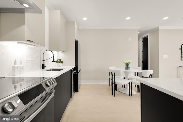 kitchen with a sink, under cabinet range hood, stainless steel range with electric cooktop, decorative backsplash, and dark cabinets